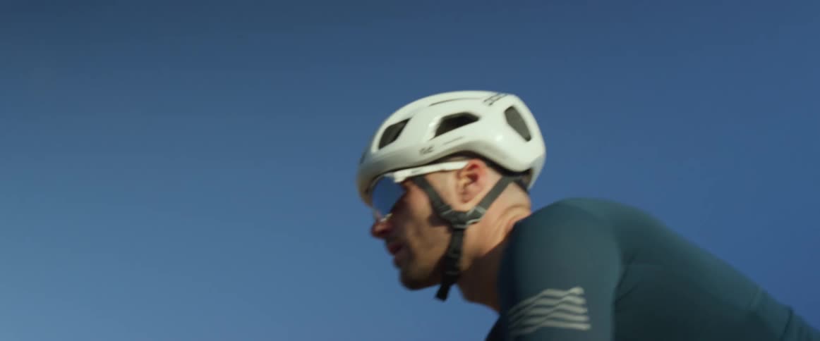 Male cyclist bikes along road with hills in the backgrund