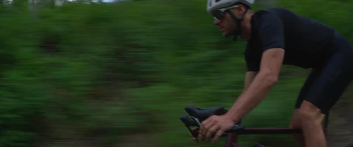 A man rides his bicycle past a forest