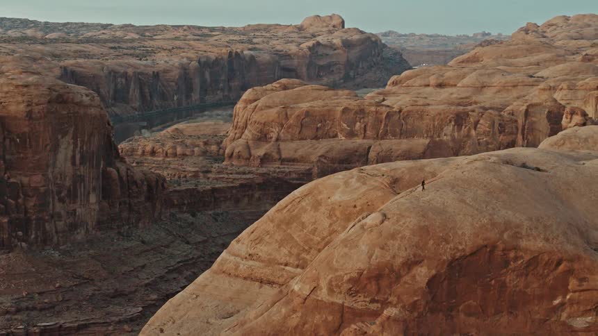 Person walks across the top of a mesa under a blue sky