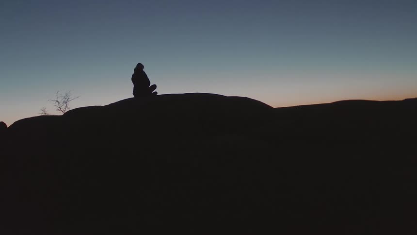 Woman sits on the top of a mountain at night
