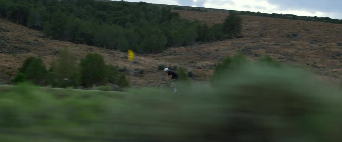 A man rides his bicycle through rolling hills