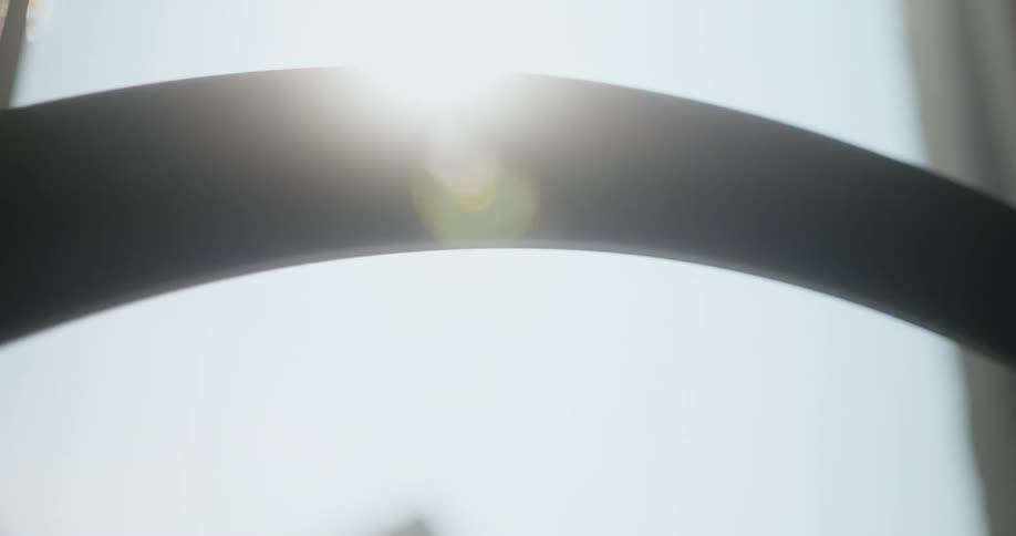 A bicycle wheel spins as the sun shines brightly upon it