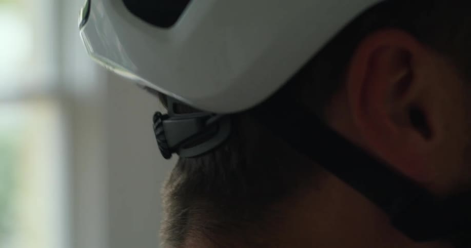 Close up of a man adjusting the straps of a bicycle helmet on the back of his head
