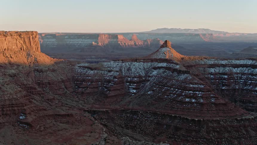 An aerial view of a canyon with snow at sunset