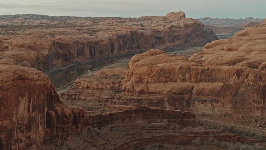 River runs between the mesas under a cloudy blue sky
