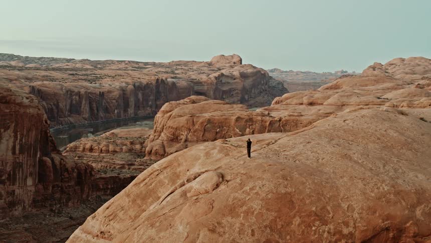 A man holds a camera up to his eyes while photographing a massive canyon