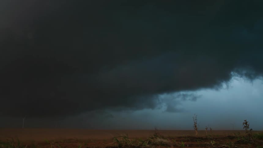 Real time shot of top soil dust being blown by severe storm winds with ominous and dark storm clouds in the background skyline