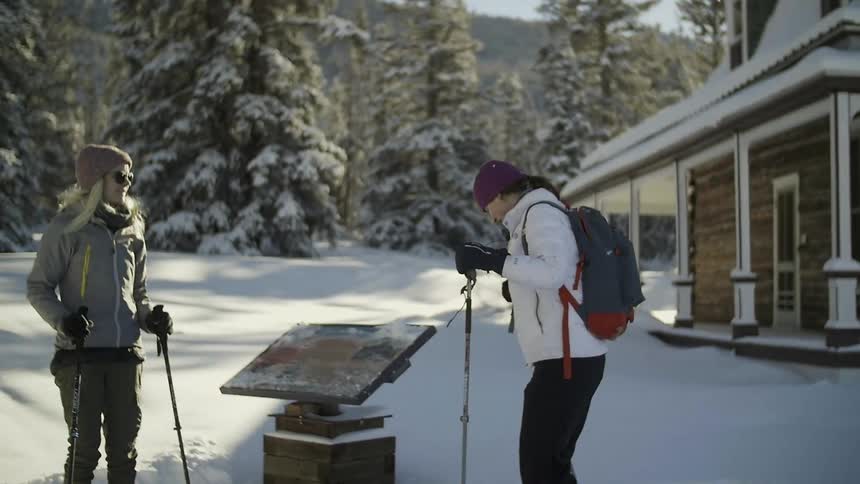 A woman walks from a house towards another woman in the snow