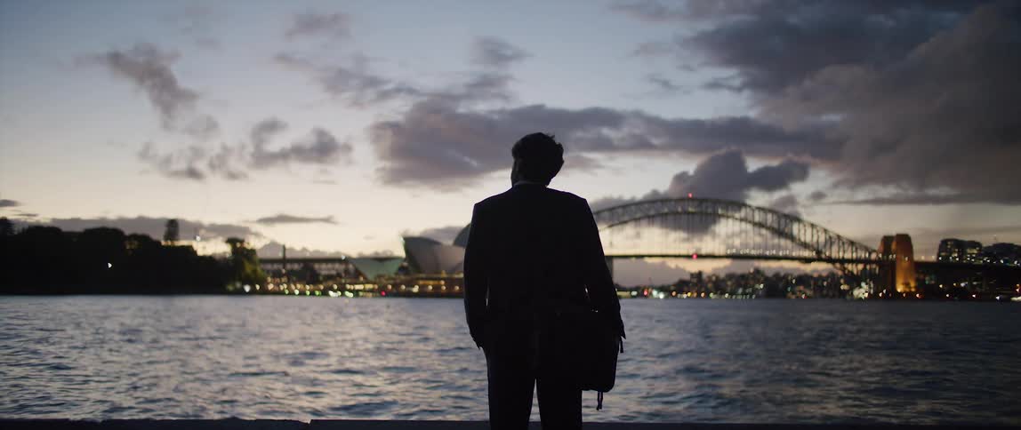 A man stands by the water at sunset