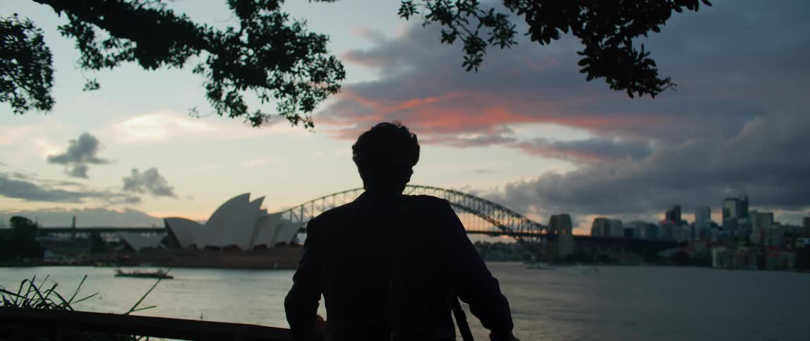 A man is looking over the water at a city as a storm rolls in