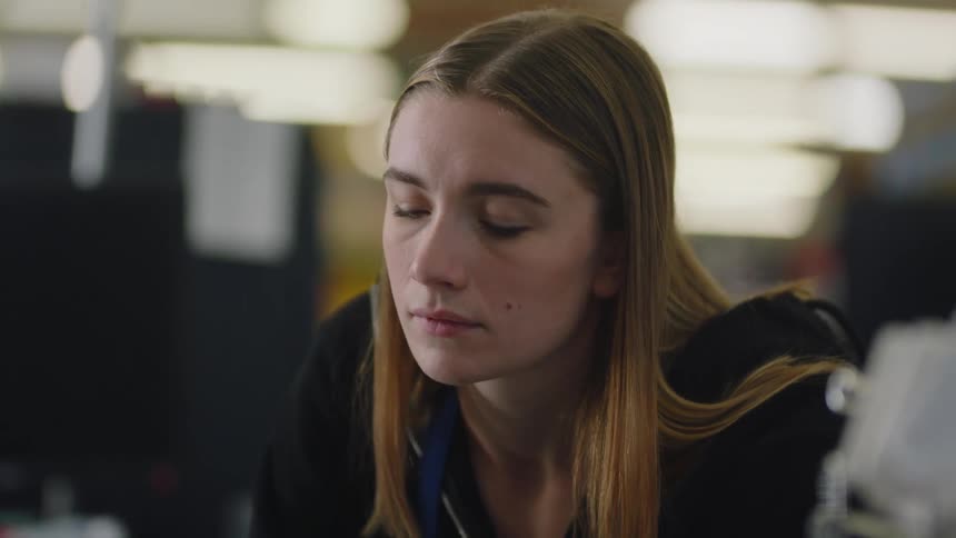 A woman looks sad and bored as she stands inside a building