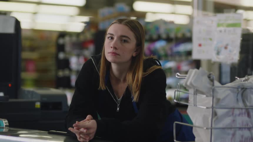 An employee leans on the counter by the register