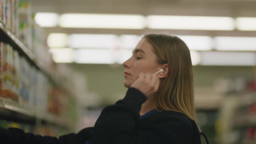 A girl puts on earbuds while working in the store