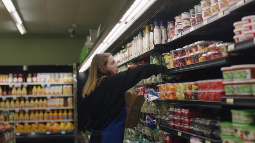 A worker is putting food on the shelves