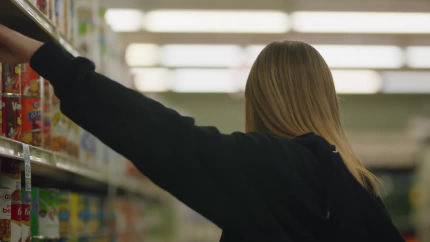 A woman dances a bit as she stocks shelves in a grocery store