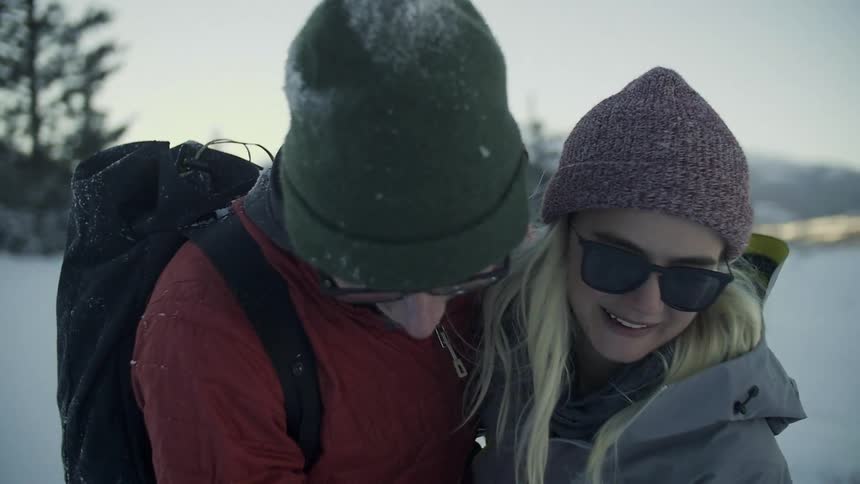 A man and woman embracing and smiling in a snow-covered landscape