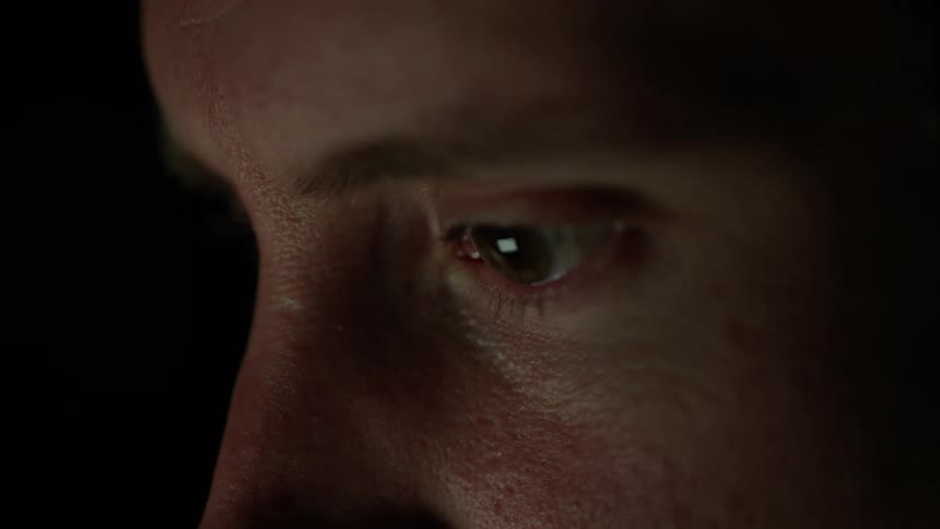 A man rubs his eyes while looking at something