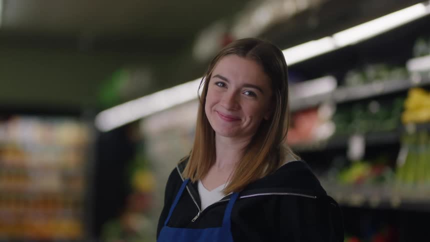 A teenage cashier smiles at work