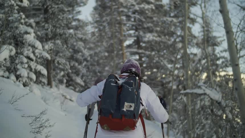 Two people are hiking on a snow covered hill