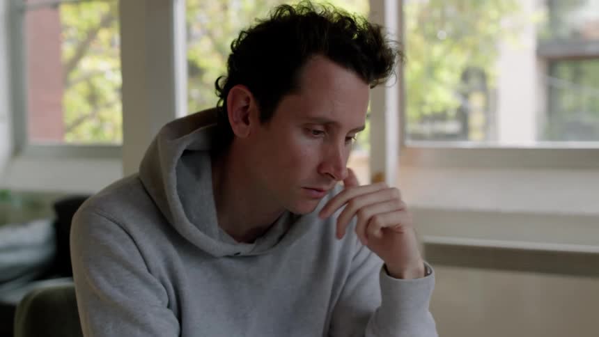 A man is sitting at a desk having a video conversation on a laptop computer