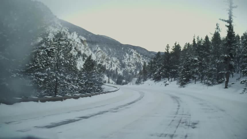 A winding road is near a cliff by a mountain