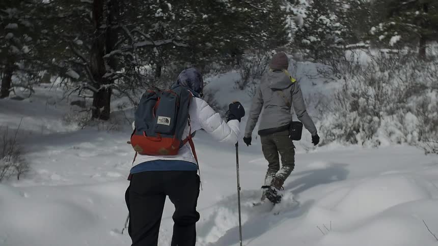 Two people snowshoe over deep snow