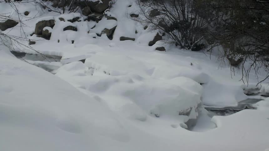 Rocks are covered by snow near a hill