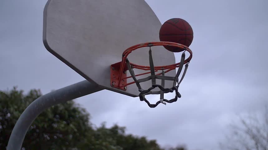 A basketball shot bounces and falls through the hoop