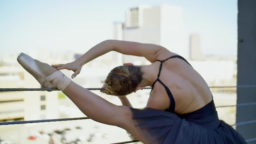 A ballerina stretching on an urban balcony