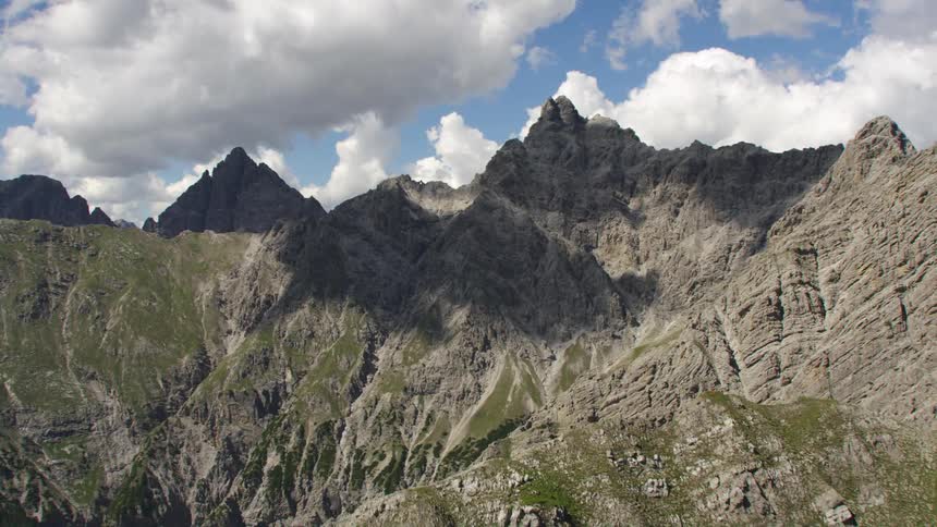 Aerial view of mountain ranges with peaks high in a cloudy sky
