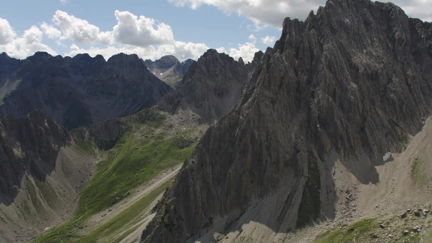 Patches of vegetation on the slopes between jagged mountain peaks during the day