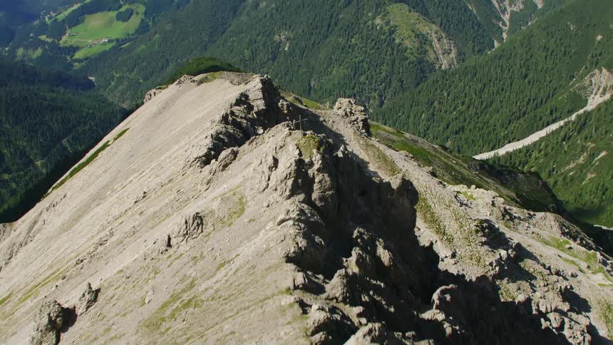 Twisting aerial footage of a steep cliff near a mountain range