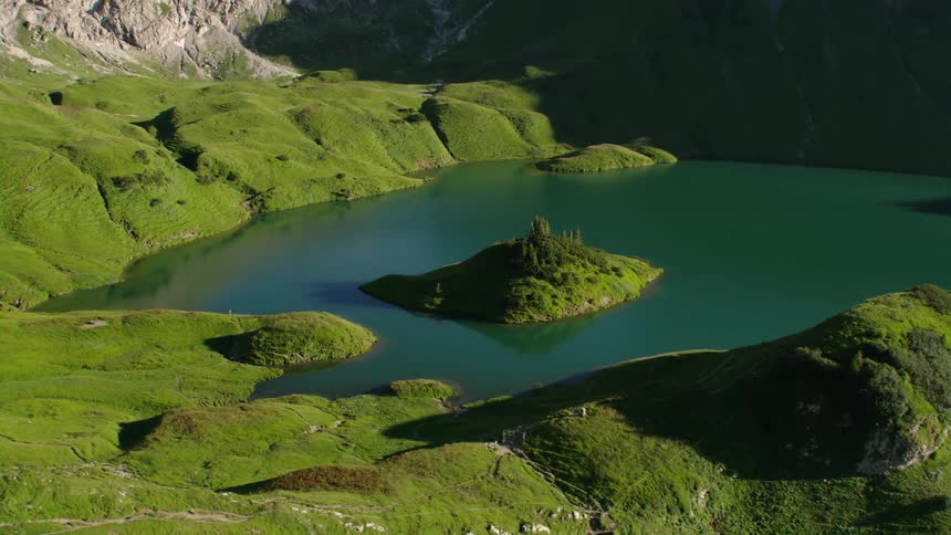 A small island protrudes from a small lack nestled between some mountains