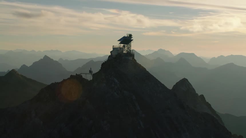 A weather station on top of a the Valluga mountain peak  with mountains in the distance