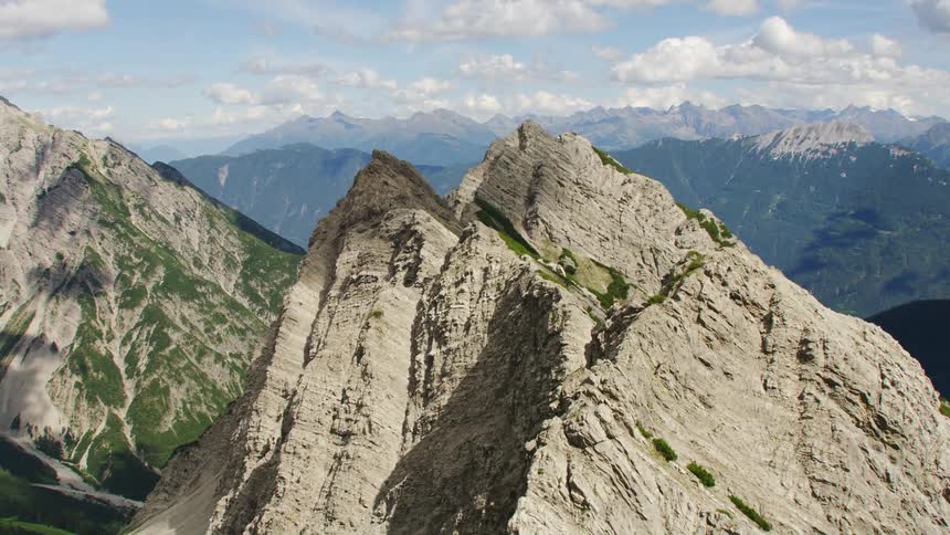 A jagged stone mountain ridge covered in patches of vegetation under the daytime sky