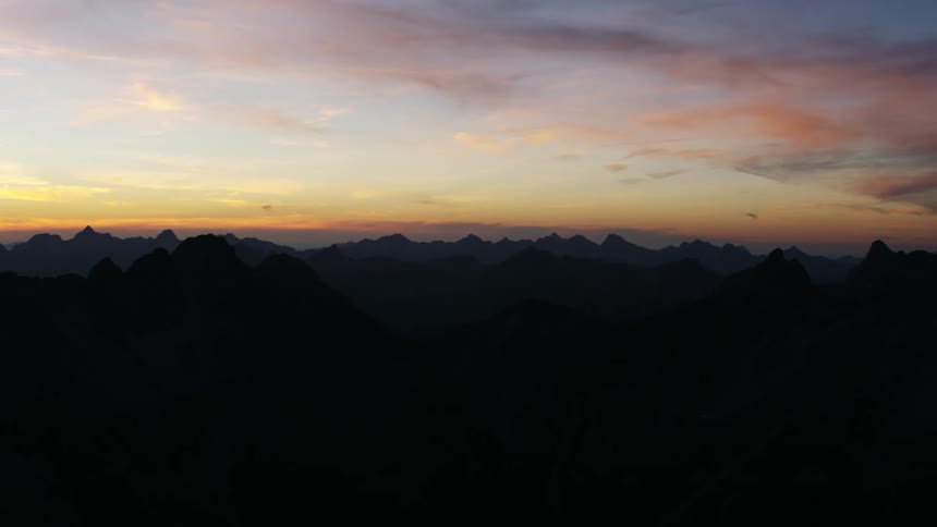 Aerial view of the silhouette of a mountain range at sunset