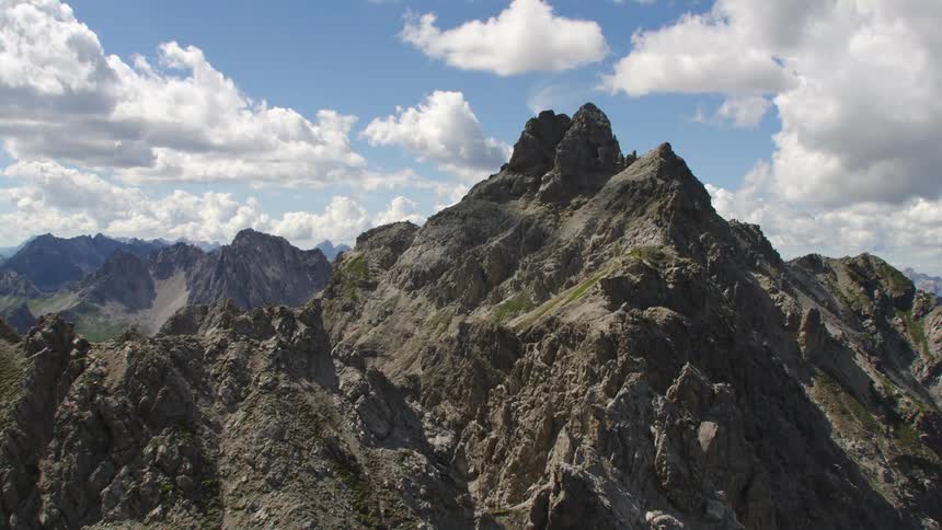 Aerial view of steep mountains under floating clouds
