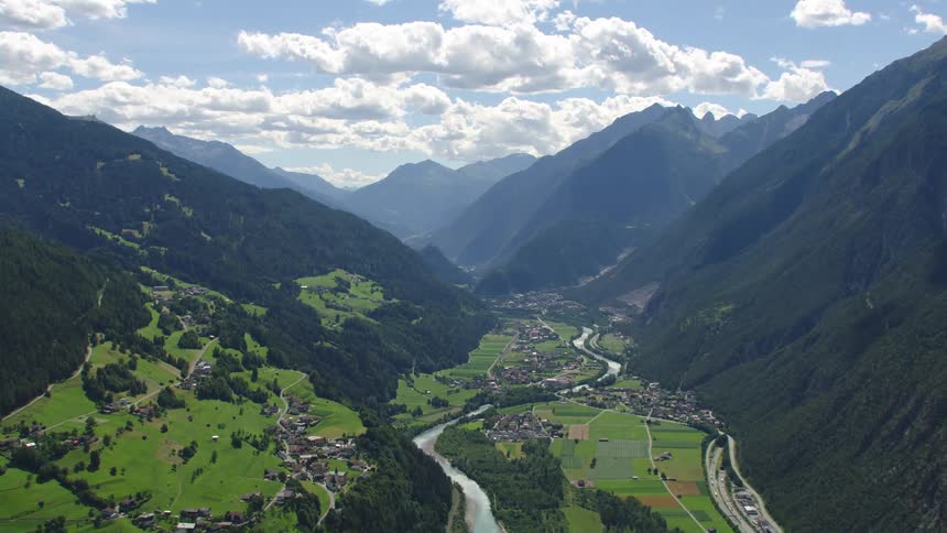 A winding river farm fields and village in the lush green oetztal mountain valley