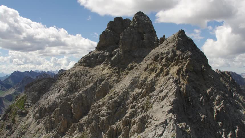 Cross stands on peak of mountain in range stretching to the horizon