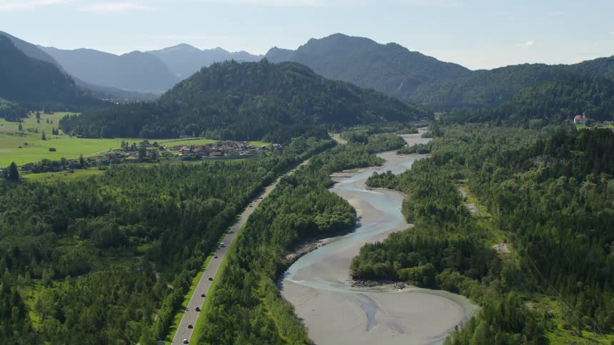 Aerial view of vehicles driving on highway between forest and river