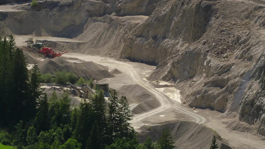 Several dirt roads can be seen within a rock quarry carved into the landscape below