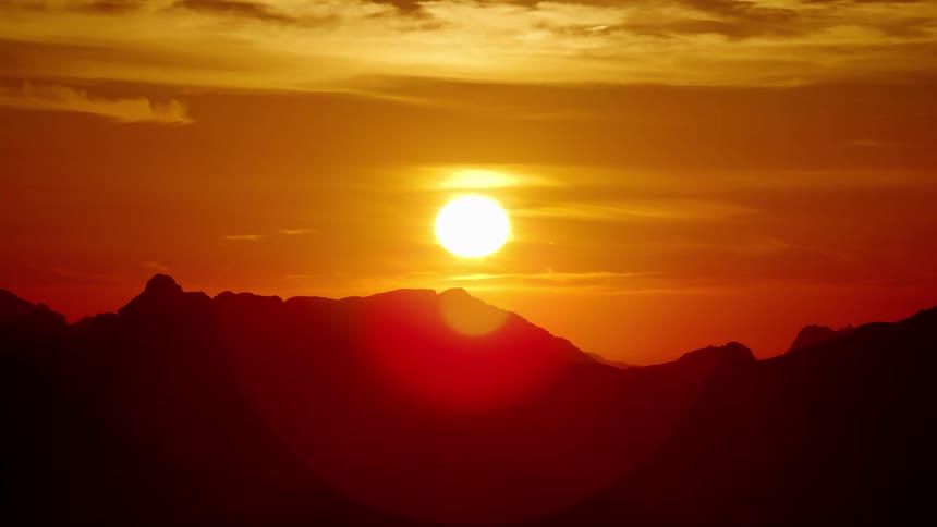 Aerial view of mountain ranges silhouetted against the sun