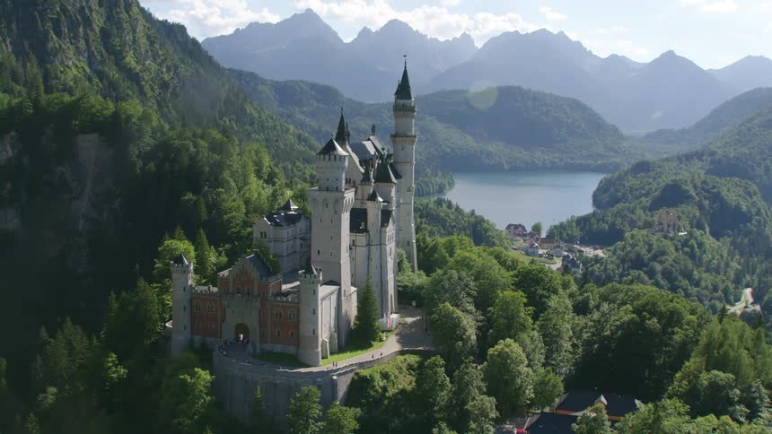 A castle atop a mountain ridge covered in forest during the day