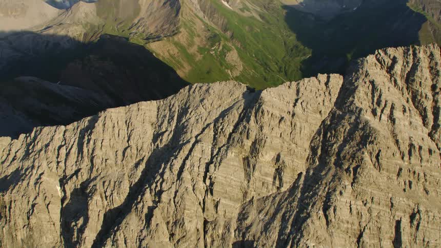 Aerial view looking down over a mountain range and mountains on the horizon in a cloudy sky