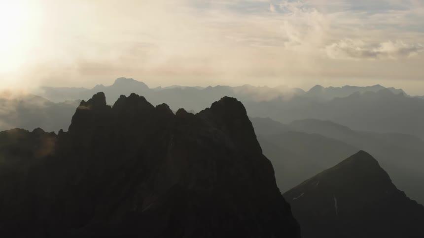 Aerial view of high mountains silhouetted against the sun