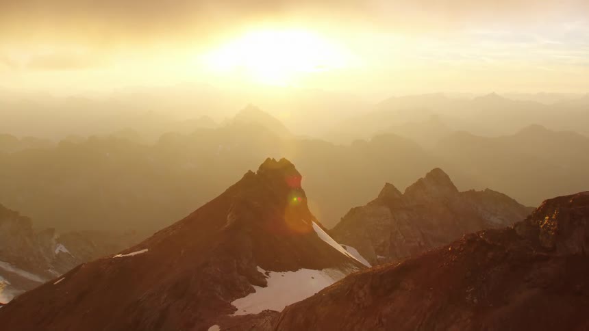 Aerial view of sun shining over snowy mountains