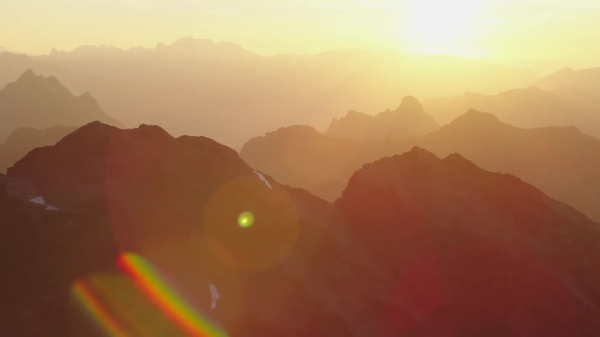 Aerial view of mountain ranges silhouetted against the sinking sun