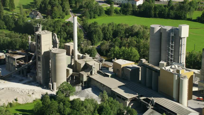 Aerial view of the buildings and silos of a factory on the fields near a small town