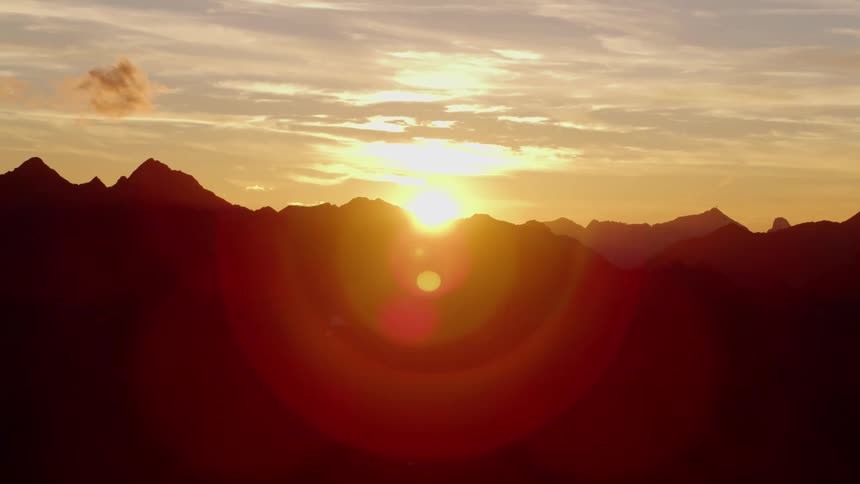Aerial view of mountain ranges silhouetted against the sinking sun