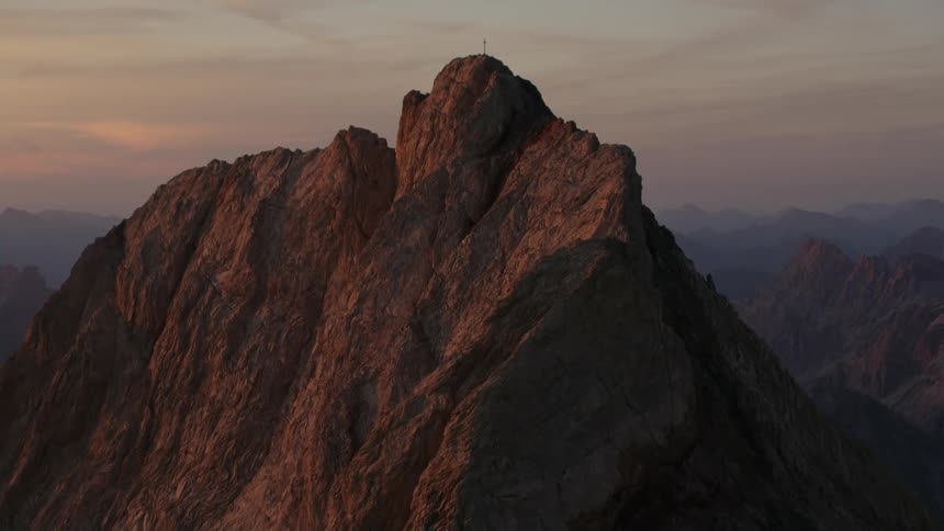 A rocky mountain ridge with a cross on the peak